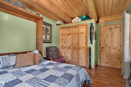 Wood-finish flooring with knotty pine doors and trim - 107 Idlehours Drive, Rural Barrhead County, AB - Indoor Photo Showing Bedroom