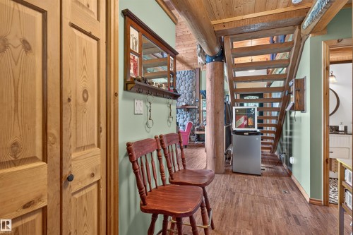 Wood-finish flooring throughout, featuring a natural wood staircase with open risers and an exposed log beam - 107 Idlehours Drive, Rural Barrhead County, AB - Indoor Photo Showing Other Room