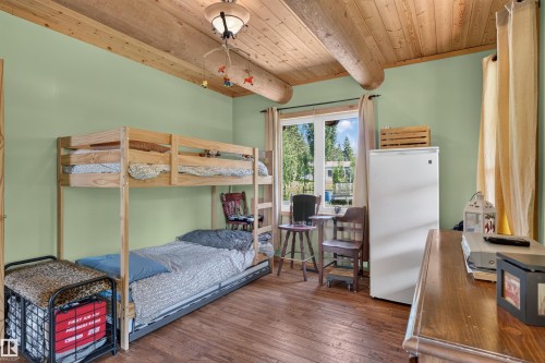 Room featuring wood-finish flooring, a wood-plank ceiling with exposed log beams, and light green walls - 107 Idlehours Drive, Rural Barrhead County, AB - Indoor Photo Showing Bedroom