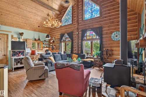 Spacious living area featuring exposed log walls, vaulted wood-paneled ceilings, and wood-finish flooring - 107 Idlehours Drive, Rural Barrhead County, AB - Indoor