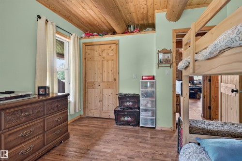 Wood-finish flooring, light green walls, wood ceiling, exposed wood beams, and a wood bi-fold closet door - 107 Idlehours Drive, Rural Barrhead County, AB - Indoor