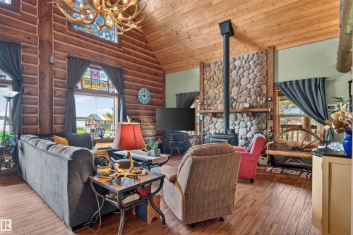 Spacious living area featuring log walls and a vaulted wood-finish ceiling - 107 Idlehours Drive, Rural Barrhead County, AB - Indoor With Fireplace