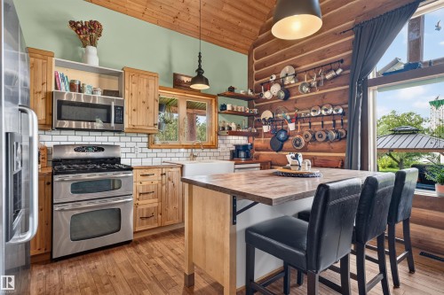 Kitchen featuring wood-finish flooring, natural wood cabinetry, stainless steel appliances, and a farmhouse sink - 107 Idlehours Drive, Rural Barrhead County, AB - Indoor Photo Showing Kitchen