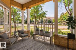 Covered porch with decorative columns, textured wall finish, and white railing - 