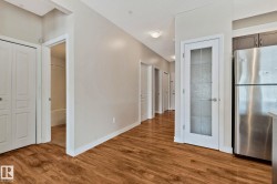 Spacious hallway featuring warm wood-finish flooring, clean white trim throughout, and multiple white panel doors - 