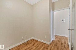 Neutral wall paint, wood-finish flooring, white baseboards, and a paneled interior door with a brushed nickel handle - 