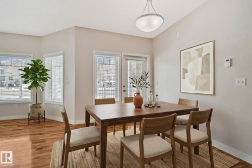 Dining area with wood-finish flooring, multiple windows featuring blinds, and a frosted glass dome pendant light fixture - #120 8931 156 St Nw, Edmonton, AB - Indoor Photo Showing Dining Room