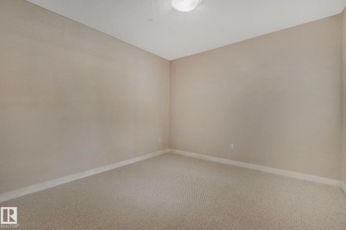 Spacious corner bedroom featuring neutral-toned walls, recessed ceiling lighting, and neutral carpet flooring - #120 8931 156 St Nw, Edmonton, AB - Indoor Photo Showing Other Room