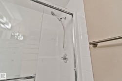 Shower enclosure with clear glass doors, white tiled walls, a brushed nickel showerhead, and a coordinating single-handle control - 