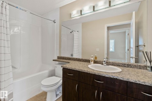 Full bathroom featuring a single vanity with a granite-style countertop, integrated sink, and dark wood-finish cabinetry - #120 8931 156 St Nw, Edmonton, AB - Indoor Photo Showing Bathroom