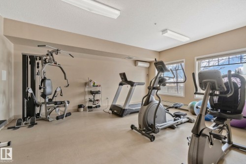 Fitness room featuring two large windows, neutral-toned walls, and overhead fluorescent lighting - #120 8931 156 St Nw, Edmonton, AB - Indoor Photo Showing Gym Room