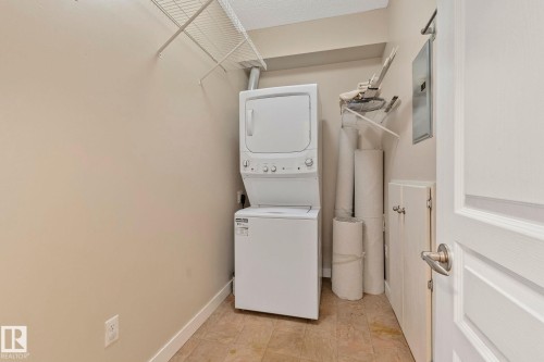 Laundry area featuring a stacked washer and dryer, wire shelving, and neutral wall paint - #120 8931 156 St Nw, Edmonton, AB - Indoor Photo Showing Laundry Room