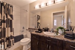 Brown wood-finish vanity with a built-in sink, stone-finish countertop, and wall-mounted mirror - 