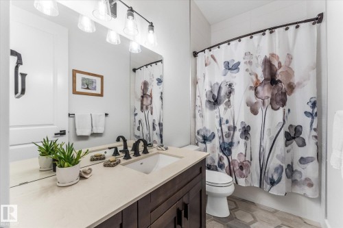 Bathroom featuring a vanity with a light-toned countertop, integrated sink, and dark bronze-finish fixtures - #52 Riverstone Close, Rural Sturgeon County, AB - Indoor Photo Showing Bathroom