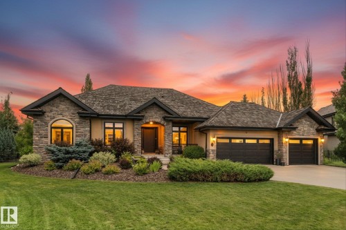 Stone and stucco facade featuring a multiple-car garage, pitched shingle roof, arched and rectangular window designs, and established landscaping - #52 Riverstone Close, Rural Sturgeon County, AB - Outdoor