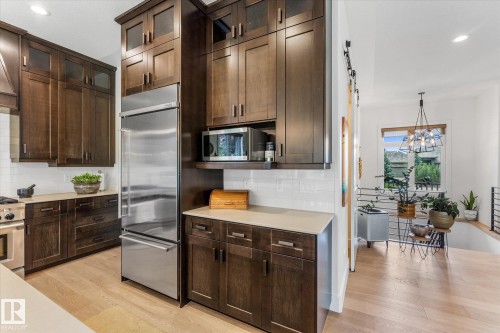 Kitchen featuring dark wood-finish cabinetry, stainless steel appliances, a subway tile backsplash, and light-toned countertops - #52 Riverstone Close, Rural Sturgeon County, AB - Indoor Photo Showing Kitchen
