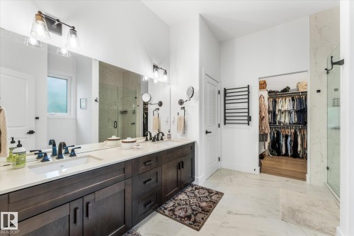 Bathroom featuring a dual vanity with dark wood cabinetry, white countertops, and black fixtures - #52 Riverstone Close, Rural Sturgeon County, AB - Indoor Photo Showing Bathroom