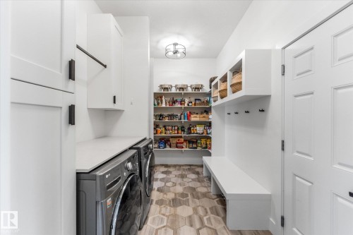Dedicated laundry area with white cabinetry, black hardware, and an expansive countertop - #52 Riverstone Close, Rural Sturgeon County, AB - Indoor Photo Showing Laundry Room