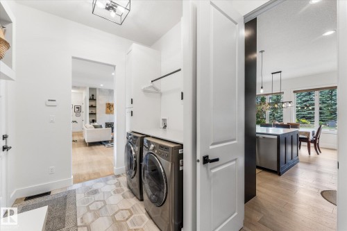Dedicated laundry area featuring a stacked washer and dryer, white cabinetry, and a wall-mounted hanging rack - #52 Riverstone Close, Rural Sturgeon County, AB - Indoor Photo Showing Laundry Room