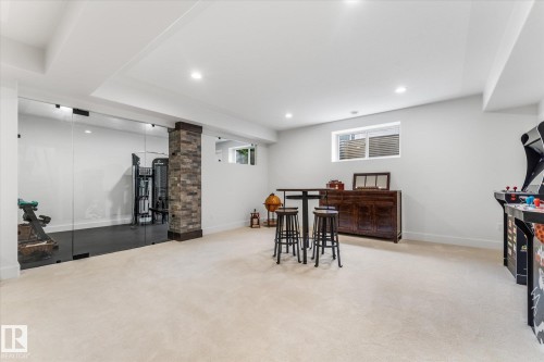 Spacious room featuring light-colored carpeting, recessed lighting, and a stone-clad support column - #52 Riverstone Close, Rural Sturgeon County, AB - Indoor