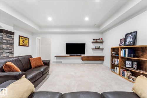 Open concept living space featuring recessed lighting, a built-in media console, wood-finish floating shelves, and a stone accent column - #52 Riverstone Close, Rural Sturgeon County, AB - Indoor Photo Showing Living Room