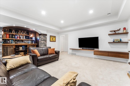 Entertainment room featuring , stone-clad architectural columns, recessed lighting, and a floating wood-finish media console - #52 Riverstone Close, Rural Sturgeon County, AB - Indoor