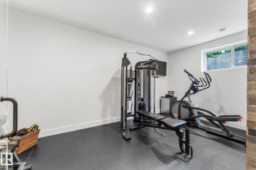 Dedicated fitness space featuring resilient black flooring, clean white walls, a single window with horizontal blinds, and recessed ceiling lighting - #52 Riverstone Close, Rural Sturgeon County, AB - Indoor Photo Showing Gym Room