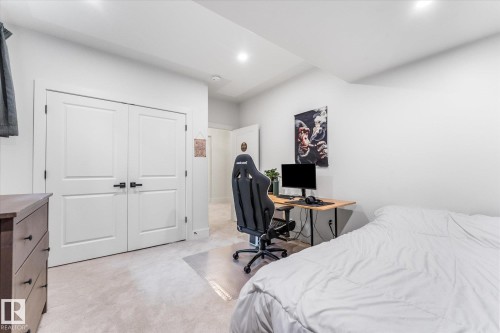 Recessed lighting illuminates this room featuring light-colored carpeting, white walls, and bright white double closet doors with dark hardware - #52 Riverstone Close, Rural Sturgeon County, AB - Indoor Photo Showing Bedroom
