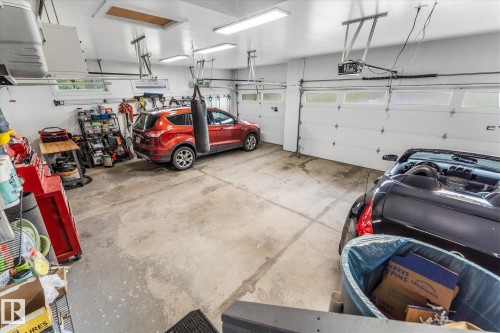 Spacious garage with concrete flooring and multiple overhead garage doors featuring frosted glass panels - #52 Riverstone Close, Rural Sturgeon County, AB - Indoor Photo Showing Garage