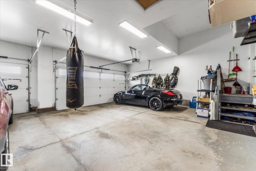 Spacious garage with concrete flooring and multiple overhead fluorescent light fixtures - #52 Riverstone Close, Rural Sturgeon County, AB - Indoor Photo Showing Garage