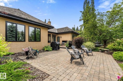 Spacious paver patio with extensive landscaping, mature trees, and a decorative water feature - #52 Riverstone Close, Rural Sturgeon County, AB - Outdoor With Deck Patio Veranda