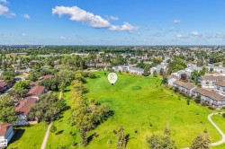 Expansive green space featuring mature trees and paved walking paths - 