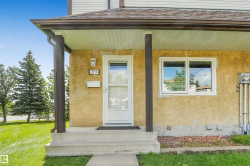 Front entry featuring stucco exterior, a white entry door, and a white-framed window - #39 14511 52 Street Nw, Edmonton, AB - Outdoor