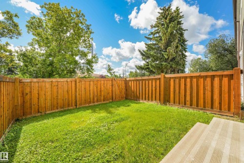 Expansive rear yard featuring green lawn, full privacy fencing, and wood-toned decking - #39 14511 52 Street Nw, Edmonton, AB - Outdoor