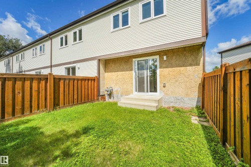 Rear exterior with a sliding glass door, two concrete steps, and a stucco finish on the lower level - #39 14511 52 Street Nw, Edmonton, AB - Outdoor With Exterior