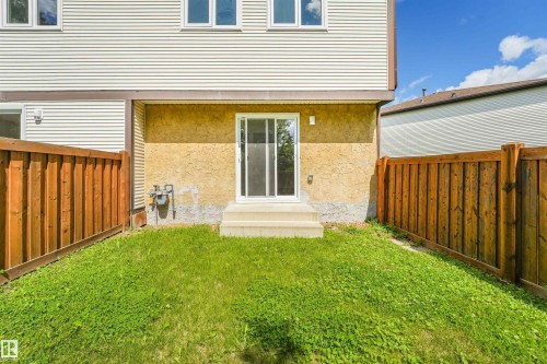Sliding glass patio door with concrete steps opening onto a private fenced yard with grass - #39 14511 52 Street Nw, Edmonton, AB - Outdoor With Exterior