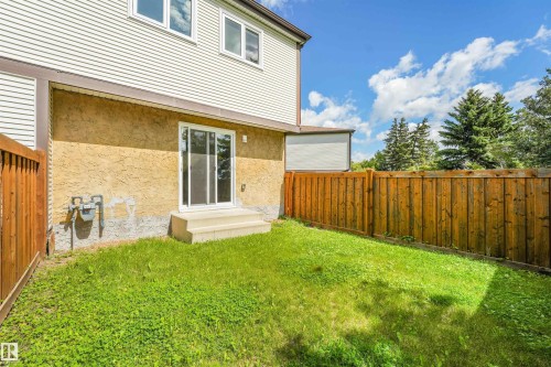 Expansive backyard featuring a sliding glass door, concrete steps, wood fencing, and a manicured lawn - #39 14511 52 Street Nw, Edmonton, AB - Outdoor