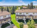 Multi-unit residential property featuring a neutral stucco and stone facade, brown asphalt shingle roofing, and covered front entrances - #39 14511 52 Street Nw, Edmonton, AB 