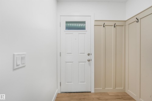 Entryway featuring a paneled door with transom window, wood-finish flooring, and wainscoting with integrated hooks - #39 14511 52 Street Nw, Edmonton, AB - Indoor Photo Showing Other Room