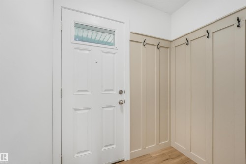 Entryway featuring a white paneled door with transom window, board and batten accent wall, multiple wall hooks, and wood-finish flooring - #39 14511 52 Street Nw, Edmonton, AB - Indoor Photo Showing Other Room