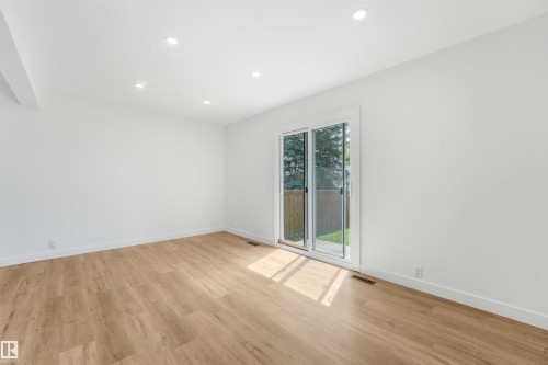 Expansive room featuring light wood-finish flooring, recessed ceiling lighting, a contemporary sliding glass door, and white baseboards - #39 14511 52 Street Nw, Edmonton, AB - Indoor Photo Showing Other Room