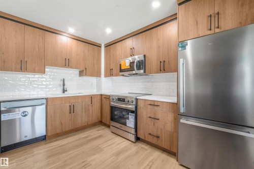 Kitchen featuring wood-finish cabinetry with black hardware, white countertops, and a subway tile backsplash - #39 14511 52 Street Nw, Edmonton, AB - Indoor Photo Showing Kitchen With Upgraded Kitchen