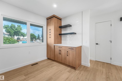 Light wood-finish flooring complements a built-in wood-finish cabinetry unit with a solid surface countertop - #39 14511 52 Street Nw, Edmonton, AB - Indoor Photo Showing Other Room