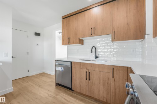 Contemporary kitchen featuring wood-finish cabinetry, white subway tile backsplash, and light-toned countertops - #39 14511 52 Street Nw, Edmonton, AB - Indoor Photo Showing Kitchen
