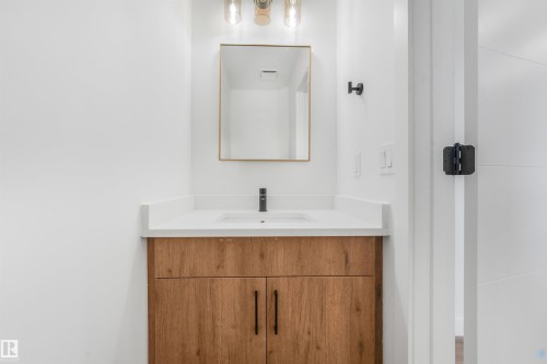 Modern vanity featuring a wood-finish cabinet, white countertop, and integrated sink - #39 14511 52 Street Nw, Edmonton, AB - Indoor Photo Showing Bathroom