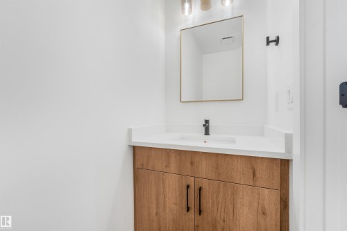 Vanity with wood-finish cabinetry, white countertop, and integrated sink - #39 14511 52 Street Nw, Edmonton, AB - Indoor Photo Showing Bathroom