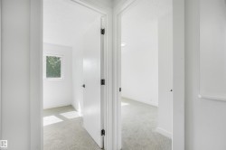 Hallway with light gray carpeting and white walls, leading to two rooms - 