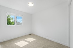 Bright room featuring a window with roller shades, neutral carpet, white walls, and a flush-mount ceiling light fixture - 