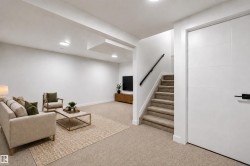 Spacious area with recessed lighting, carpet flooring, and a stairway with a black handrail - 