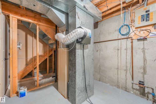 Unfinished basement space featuring exposed concrete walls, visible wooden ceiling joists, and a partial staircase framing - #39 14511 52 Street Nw, Edmonton, AB - Indoor Photo Showing Basement